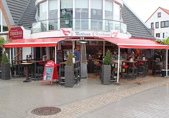 Eien rote AMrkise über den Sitzplätzen im Außenbereich eines Cafes