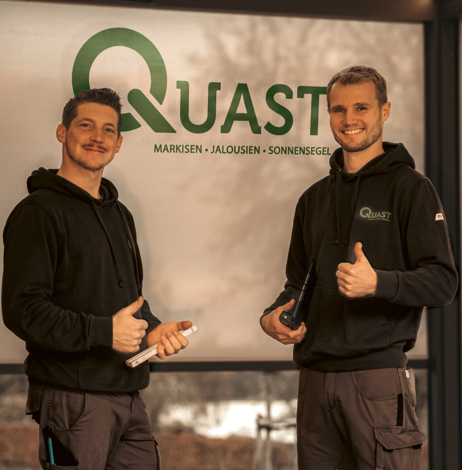 Die beiden Geschäftsführer in Montagekleidung in der Geschäftsstelle